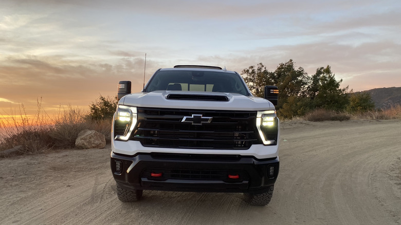 Head-on photo of the Chevrolet Silverado 2500 HD Trail Boss on a dirt road in front of a sunset