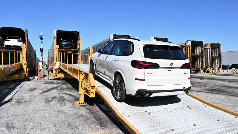 A white BMW X5 being loaded onto a train