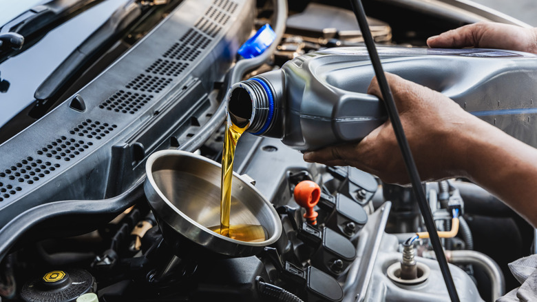 A photo of oil being poured into a car engine.