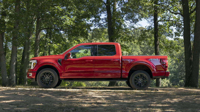 A photo of a red Ford F-150 truck in the woods.