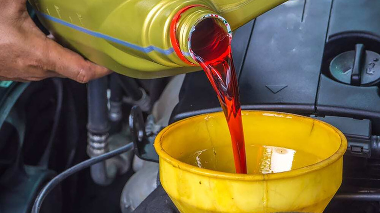 A mechanic filling a car's transmission with fluid