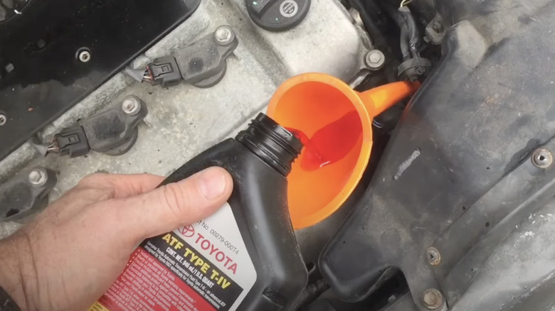 Person pouring Toyota transmission fluid into a Camry