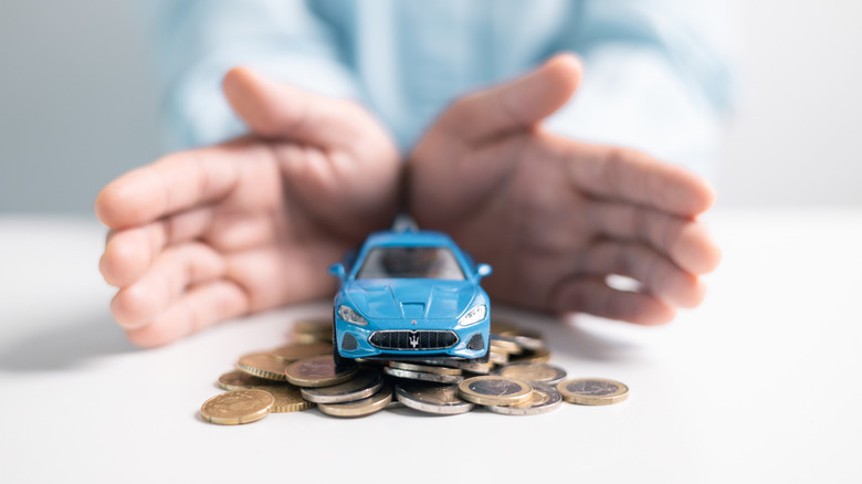 A tiny toy car sits on a pile of money