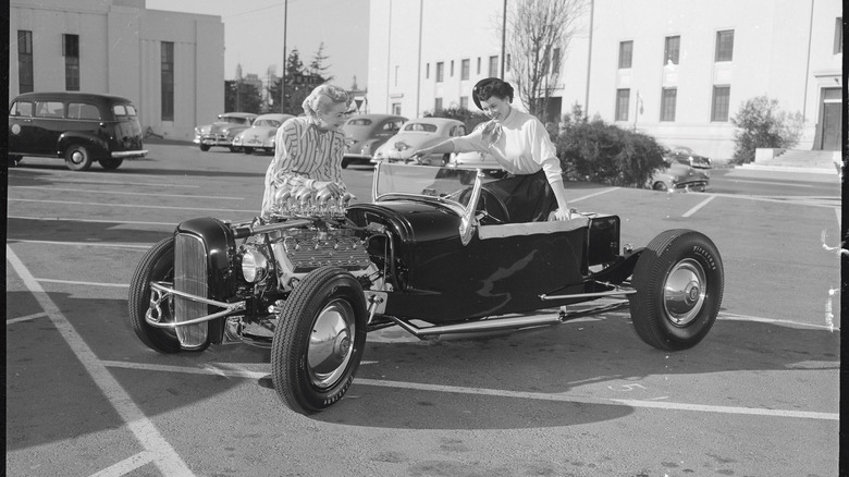 A pair of women admiring a flathead-powered hot rod.