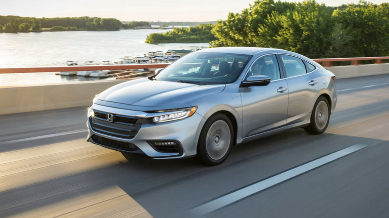 A honda insight driving over a bridge with a river in the background