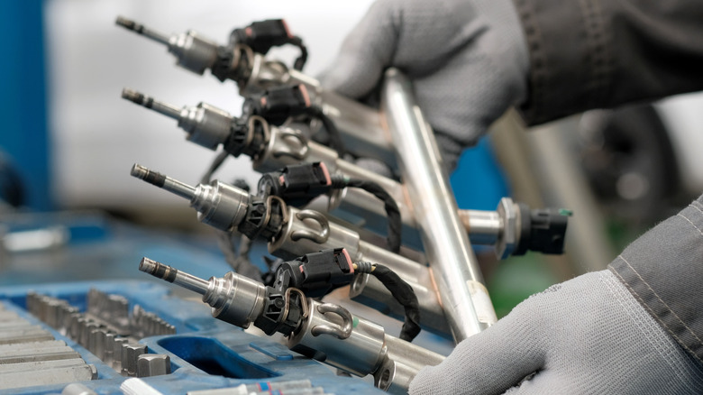 A mechanic holding a rack of fuel injectors