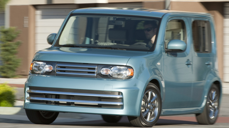 a light blue Nissan cube Krom driving around a corner