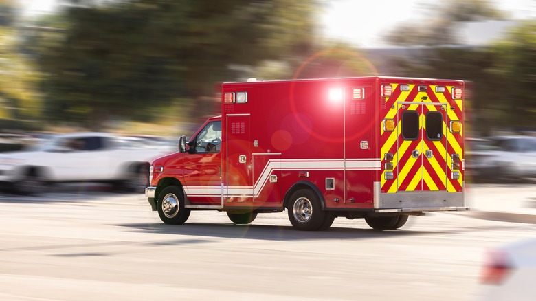 Motion panned view of an ambulance on a city street racing to the scene of an emergency.