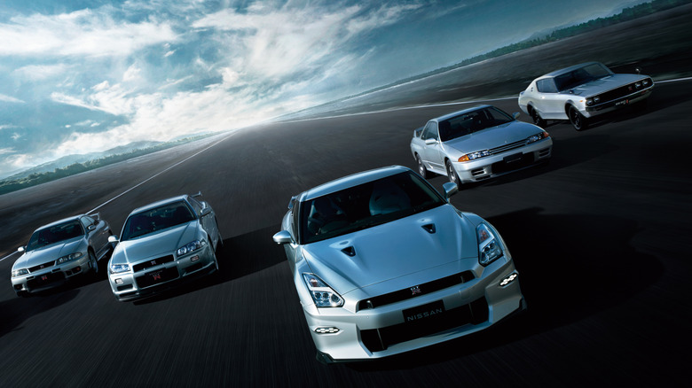 A photo of five Nissan sports cars driving on a road.