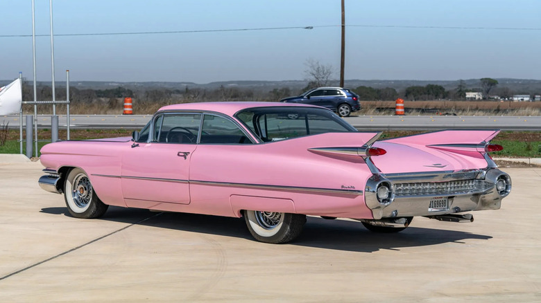 a rear three quarters of a pink cadillac coupe deville parked in a lot