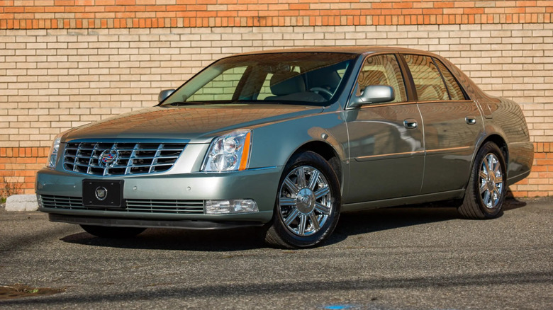 light green cadillac dts parked in front of a brick wall