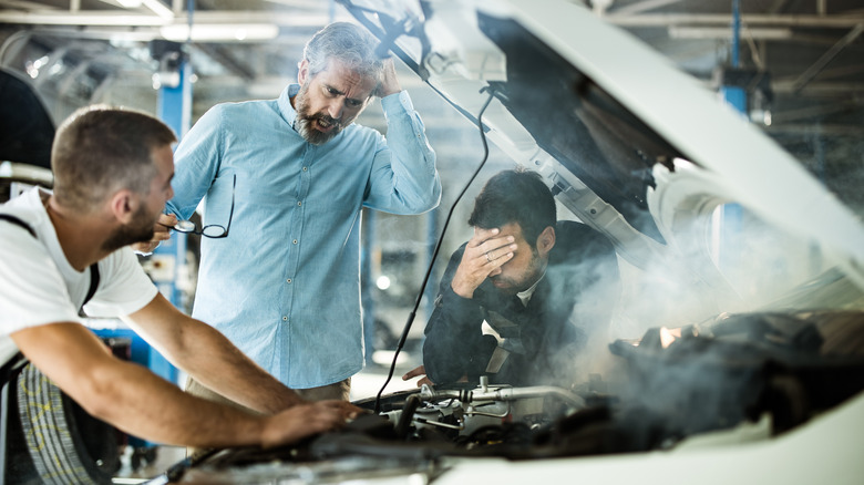 Three angry, confused guys looking into a smoking engine bay.