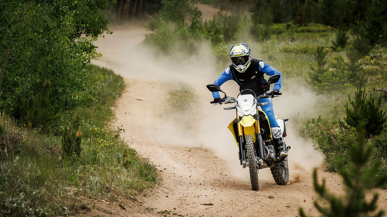 A rider on a yellow Suzuki DR-Z4S dual sport motorcycle