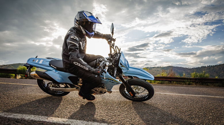 A rider on a blue Suzuki DR-Z4SM supermoto motorcycle