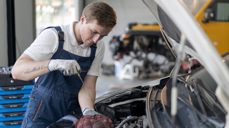 A mechanic checking the oil level on a car's dipstick.