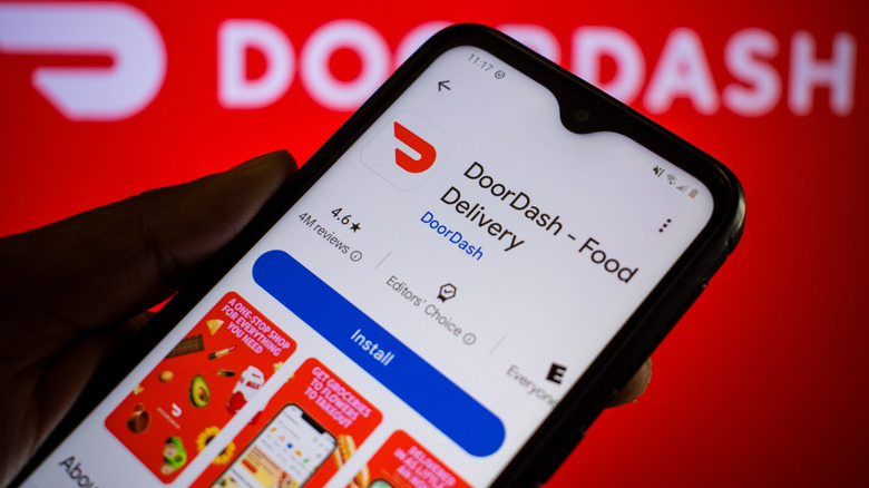 Man holds smartphone with DoorDash app on Google Play. DoorDash, Inc. is an American company operating online food ordering and food delivery.