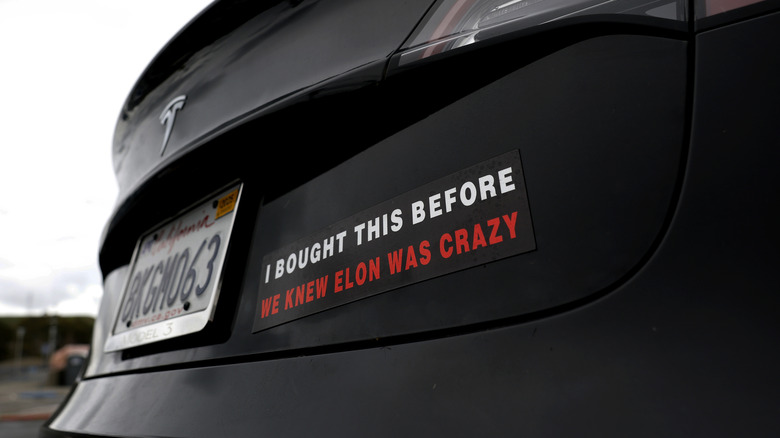 A photo of a Tesla car with a bumper sticker.