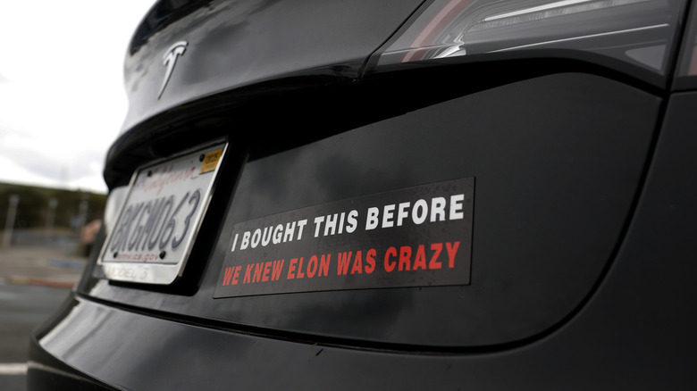 A photo of a Tesla with a bumper sticker.