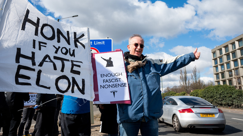 A photo of a protester holding a sign about Elon Musk.