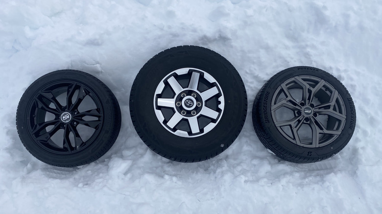 Three different wheels and tires laying on snow