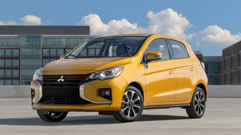 a yellow Misubishi Mirage hatchback parked on a rooftop parking lot