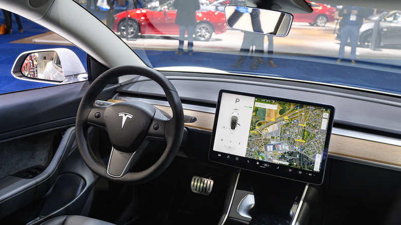 the inside of a tesla on a car show floor displaying self-driving data