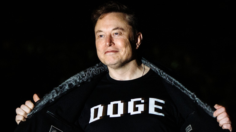 Elon Musk proudly displays a black t-shirt with DOGE on it