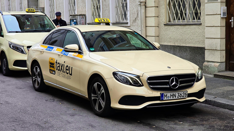 Front 3/4 view of a beige Mercedes-Benz E-Class taxi