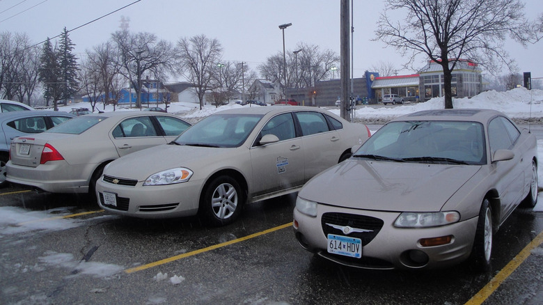 A photo of three beige cars in a parking lot.