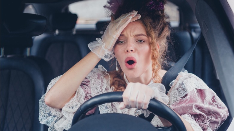 Elegance meets modern driving young woman in antique dress steers through urban setting