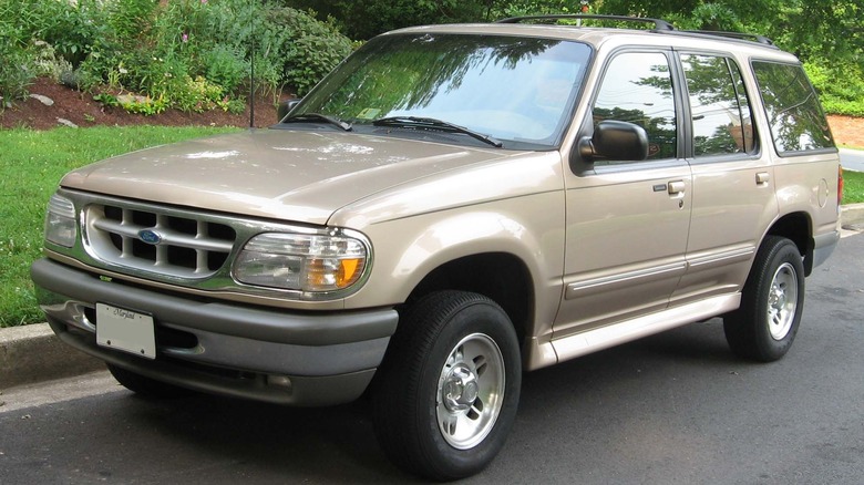 a gold ford explorer parked in front of grass