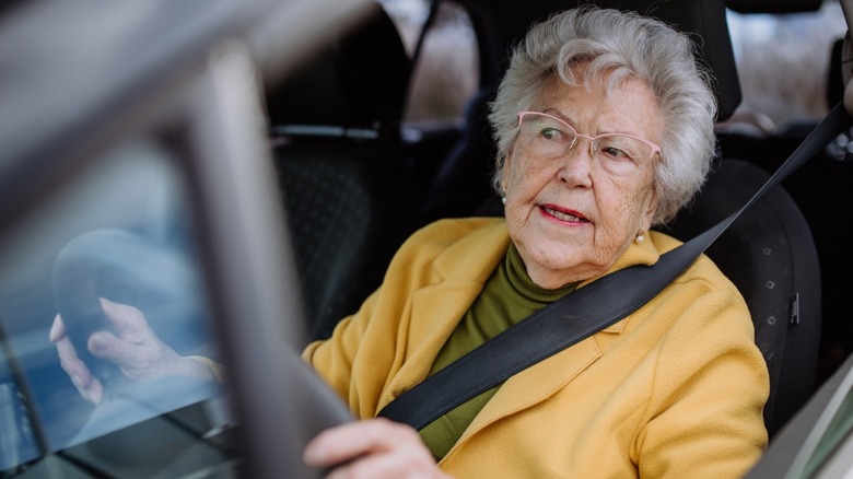 Focused senior woman driving car alone, enjoying car ride. Safe driving for elderly adults, older driver safety.