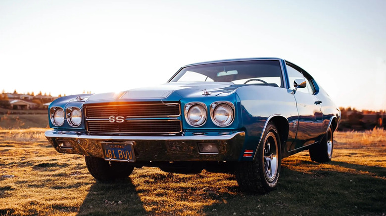 a blue Chevelle parked in front of a sunset