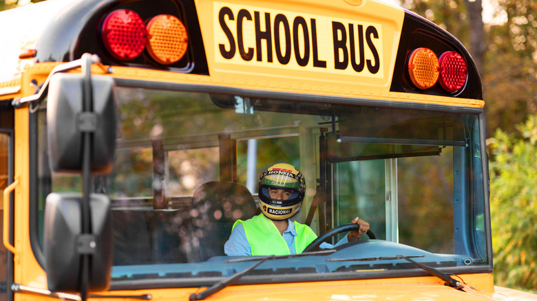 Portrait Of Happy Black Female Driver Driving Yellow School Bus, Beautiful Young African American Lady In Reflecting Vest Looking Through Window, Holding Steering Wheel An Smiling At Camera