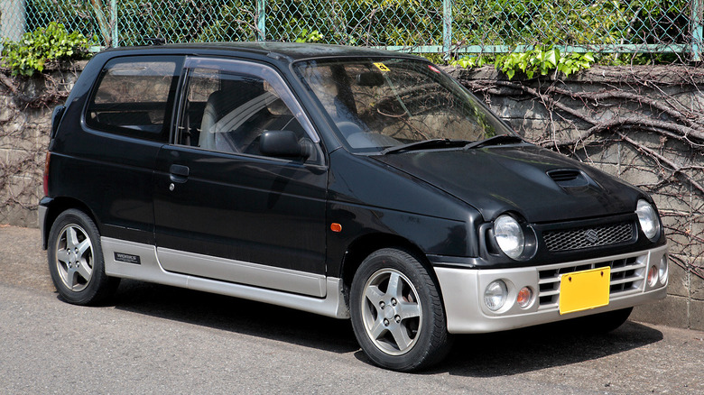 A black suzuki alto parked in front of a wall