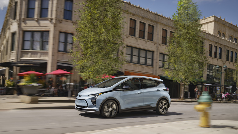 A light blue bolt driving past a building