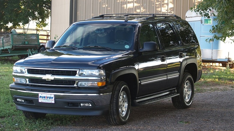 A black tahoe parked in front of a shed