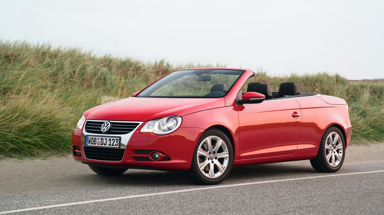 a red topless VW Eos parked in front of grasses