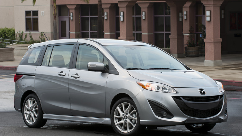 A silver Mazda 5 parked in front of a building