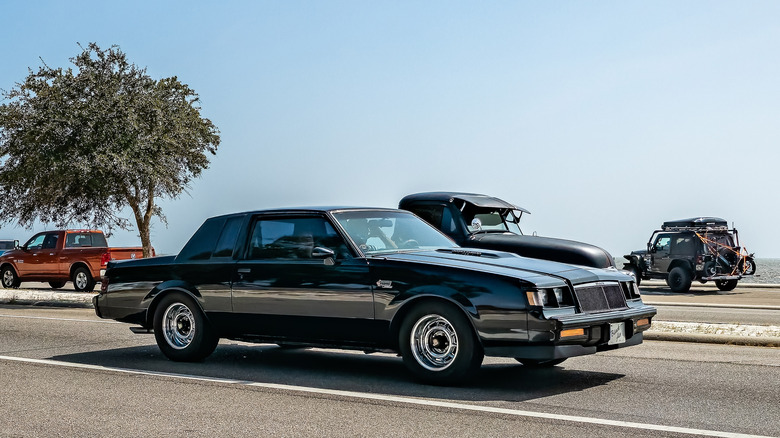 A buick grand national driving down a sunny street