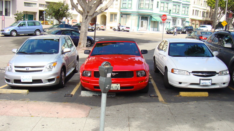 A silver Scion xA, a red Ford Mustang convertible and a white Nissan Altima