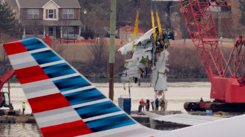 Photo of the remains of a plane being lifted from a river.