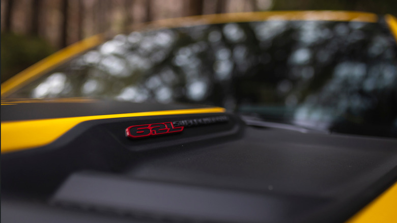 A close up of the6/2-liter supercharged badge on the hoodscoop of a yellow Ram TRX