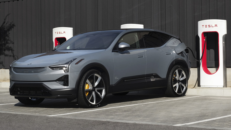 Front 3/4 view of a grey Polestar 3 plugged into a Tesla Supercharger