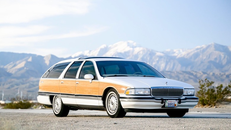 A white Buick Roadmaster estate wagon with wood side paneling parked in front of mountains