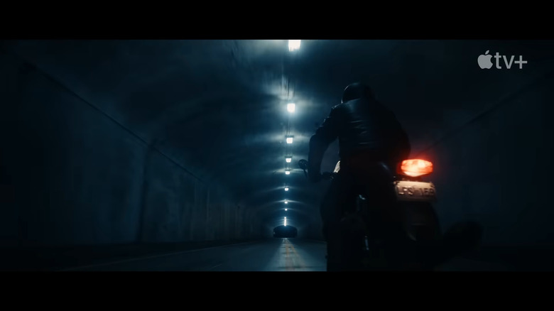 A man rides a motorcycle through a tunnel at night