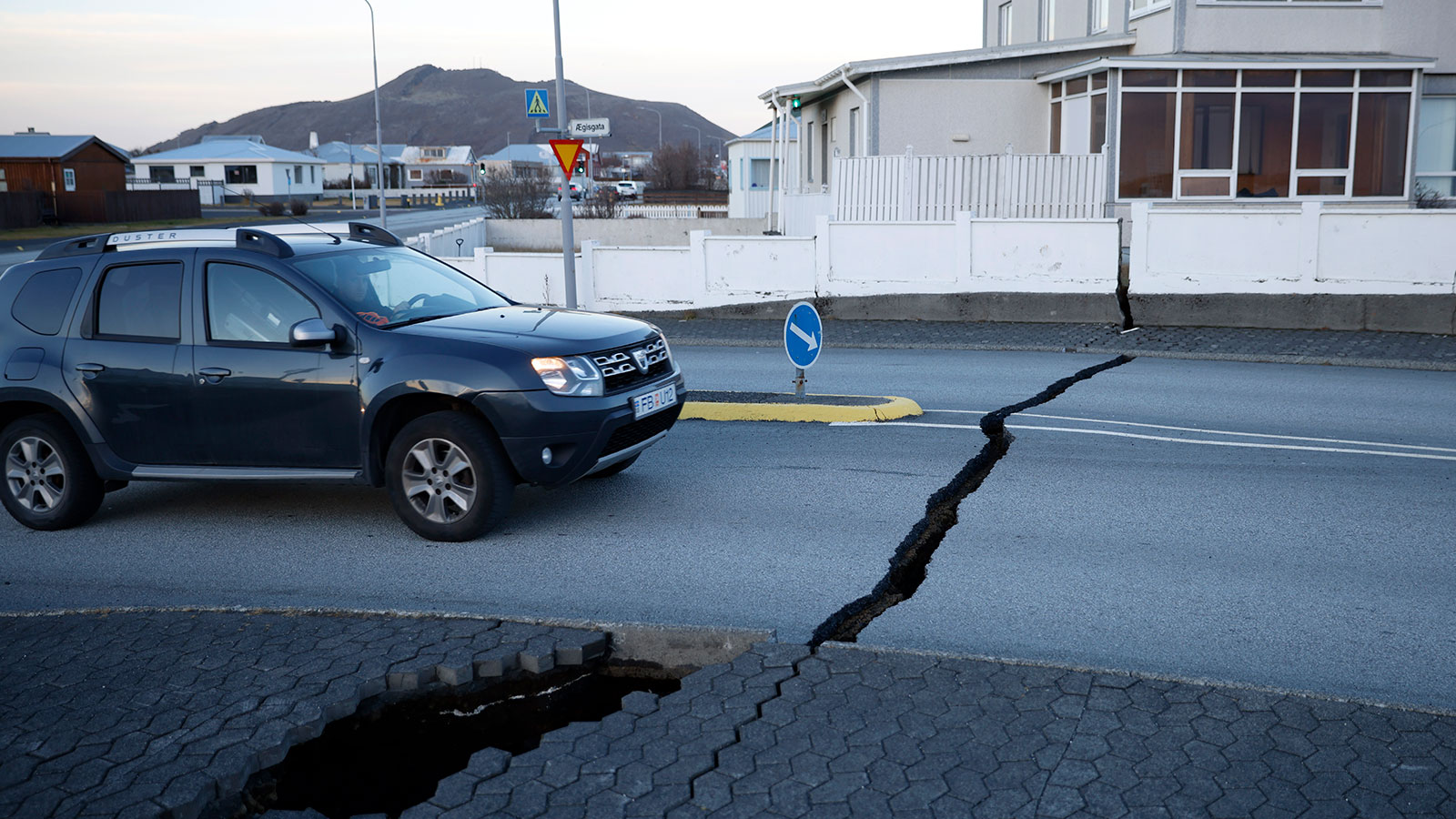 A photo of a car driving over cracked roads in Iceland. 