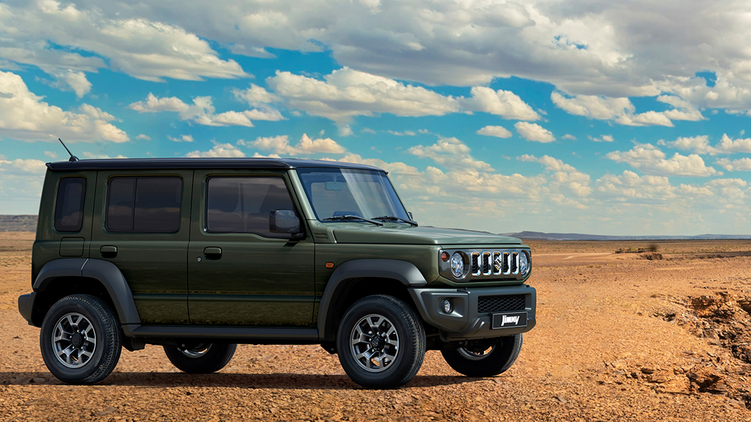 a dark green jimny nomade parked in a desert