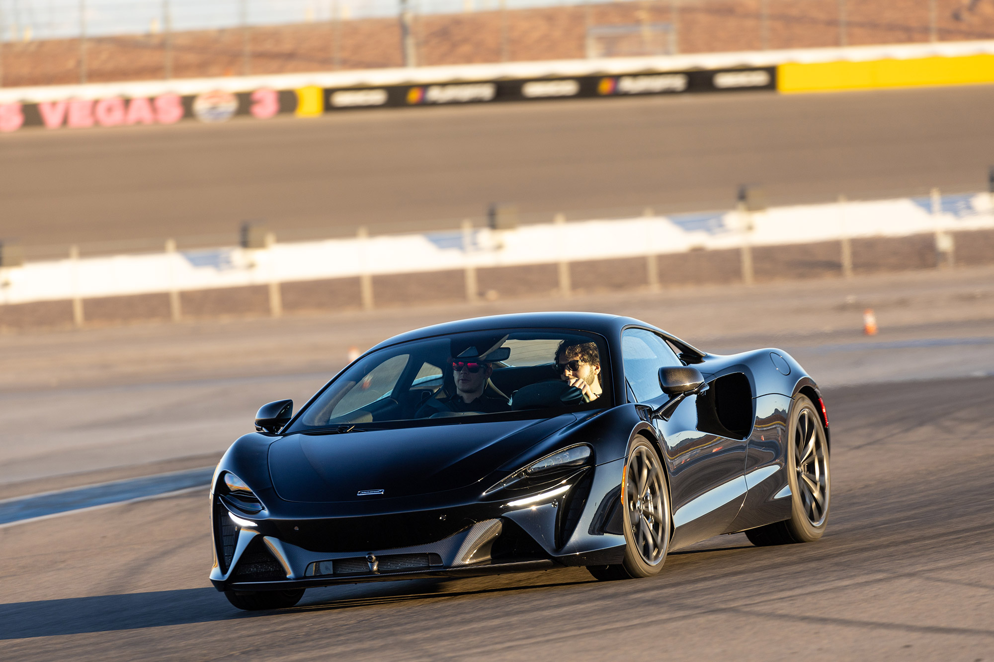 A black McLaren Artura being driven on a racetrack.