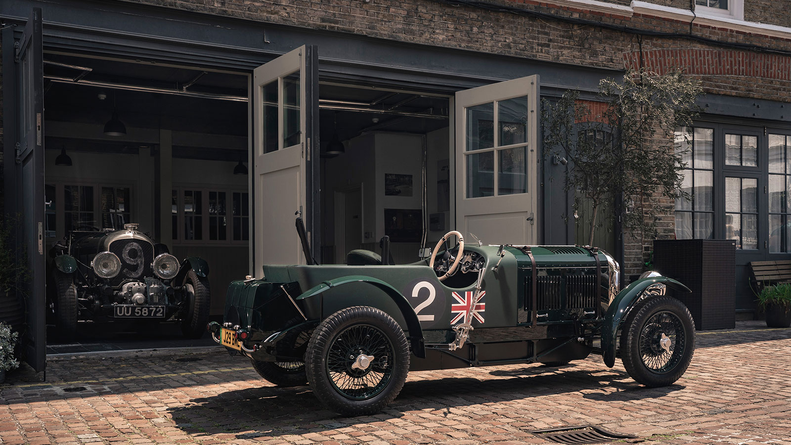 A photo of a green Bentley Blower replica outside a garage. 